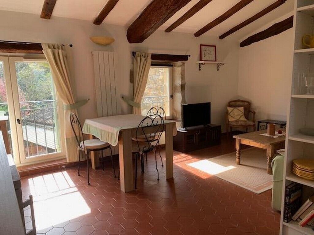 Ein Zimmer mit Esstisch, Stühlen, Fernseher und Bücherregal.