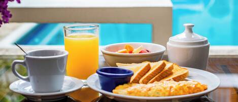 A breakfast setting with a glass of orange juice, a cup, toast, and a bowl of fruit by a poolside.