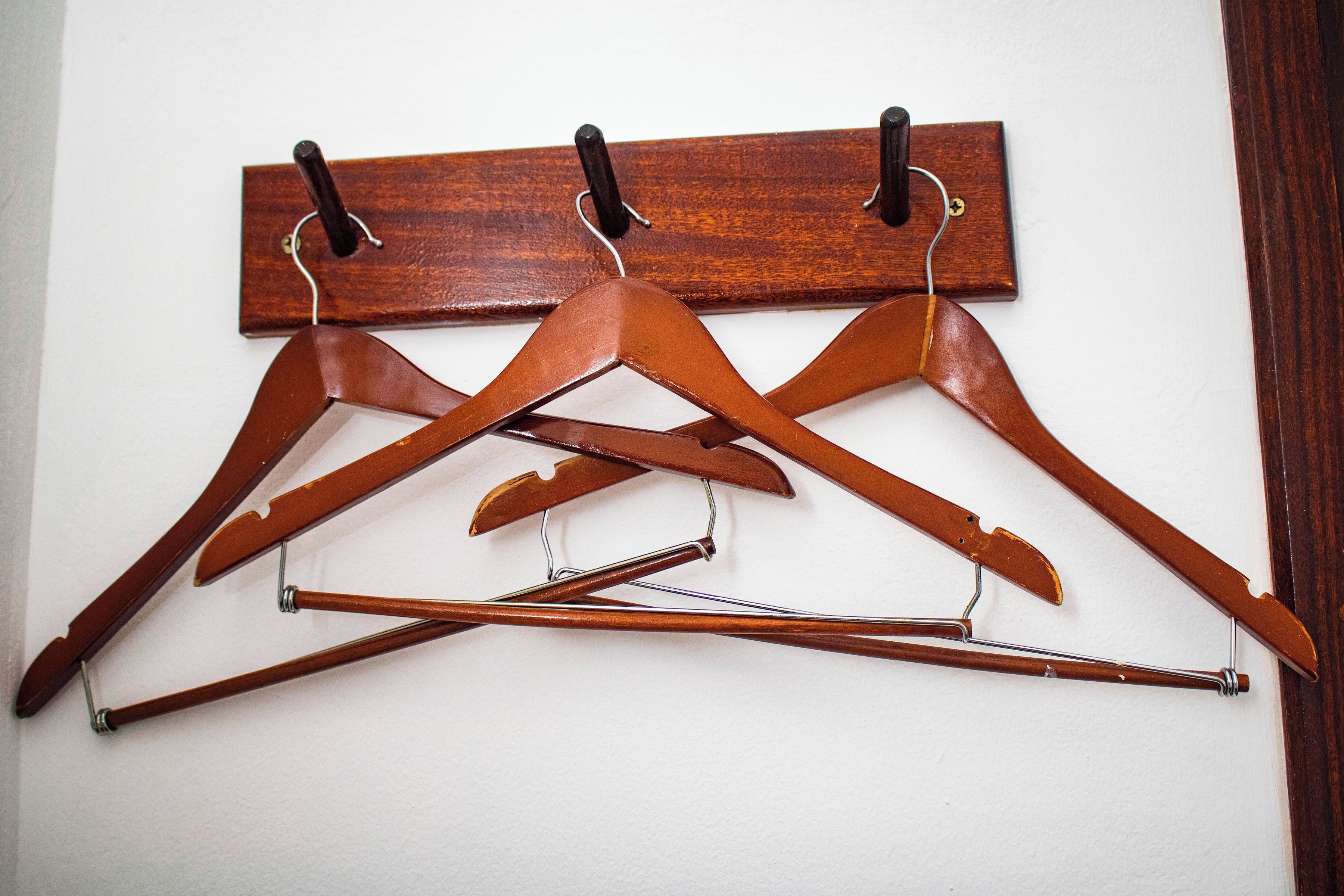 Un perchero de madera con tres perchas y una percha con barra de metal.