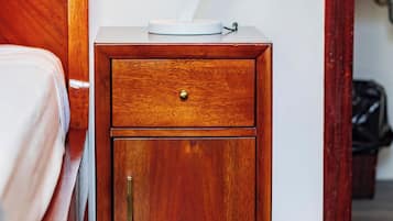 A wooden nightstand with a drawer, a lamp, and a small table with a white object on top.