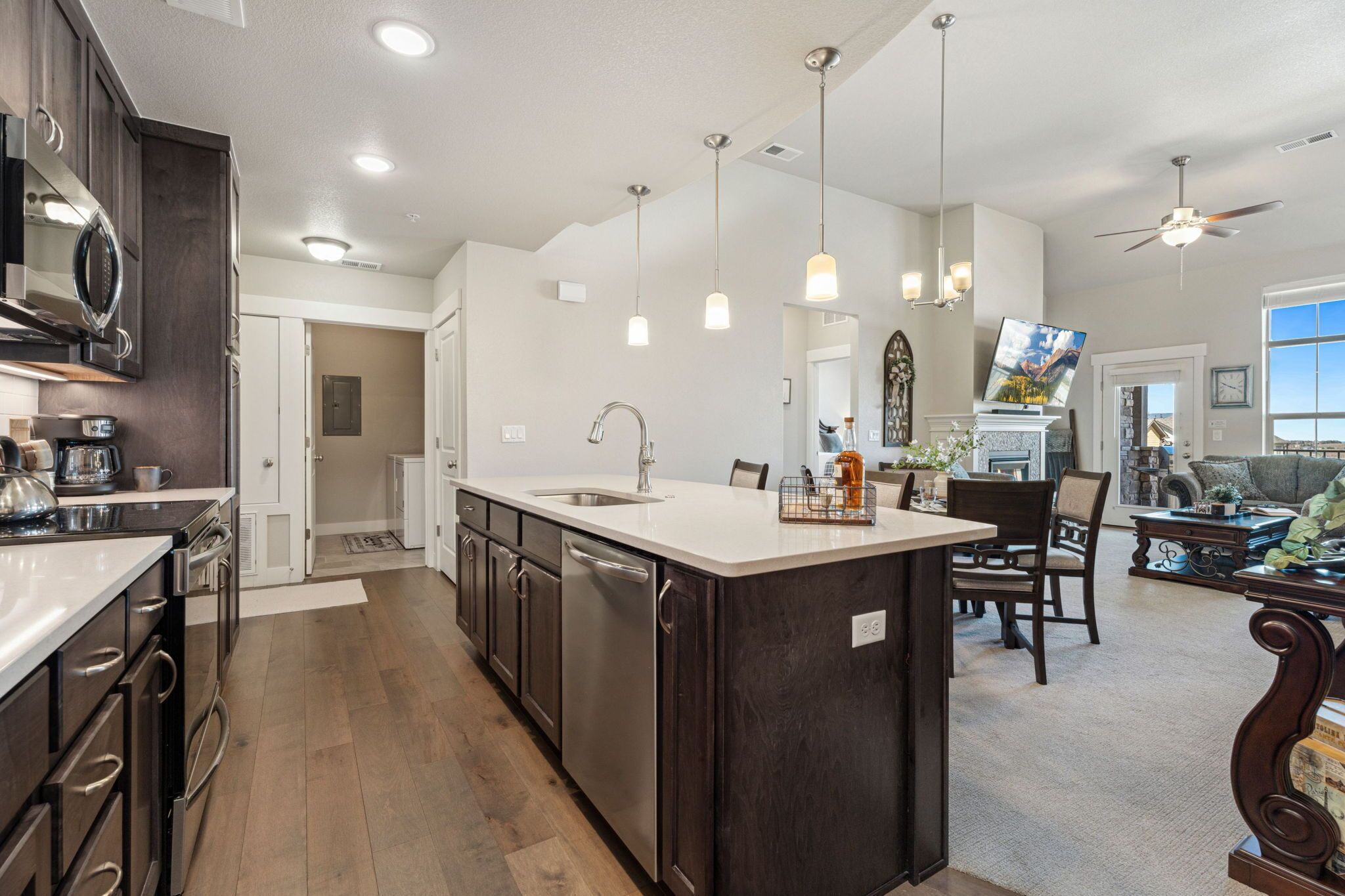 A modern kitchen with dark wood cabinets, a stainless steel dishwasher, and a white countertop.