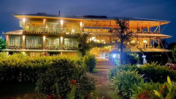 A multi-story building with a covered outdoor area, a pathway leading to the entrance, and well-maintained gardens.