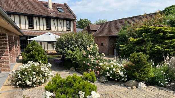 A traditional house with a garden featuring white flowering plants and a wooden deck. - Villa Lion-Mallet (MIANNAY)