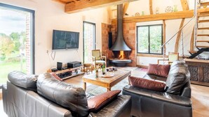 Ein geräumiges Wohnzimmer mit Ledersofas, einem Kamin, einem Fernseher und einer Treppe.
