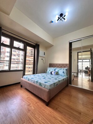 Quarto com cama, janela, ar condicionado e espelho.