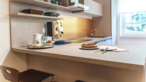 A modern kitchen with a countertop, a chair, and a dining table set with plates, a cake, and a teapot.