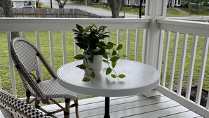 En overdækket veranda med et rundt bord og to fletstole.