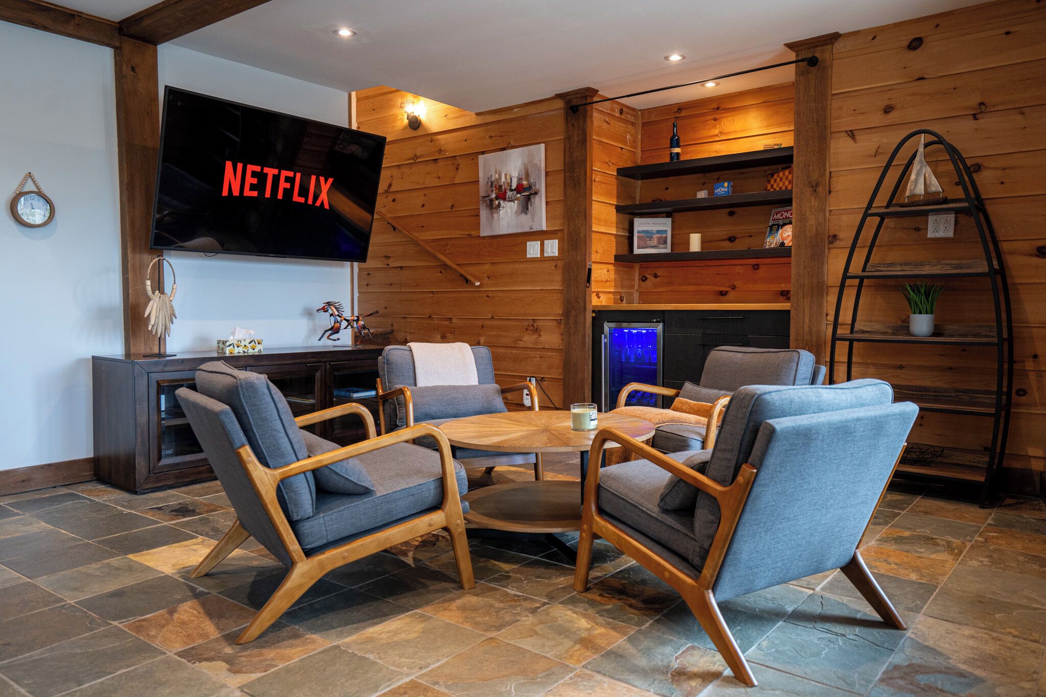 A cozy living room with a wooden interior, a flat-screen TV, a fireplace, and a coffee table.
