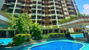 A high-rise building with a swimming pool in front.