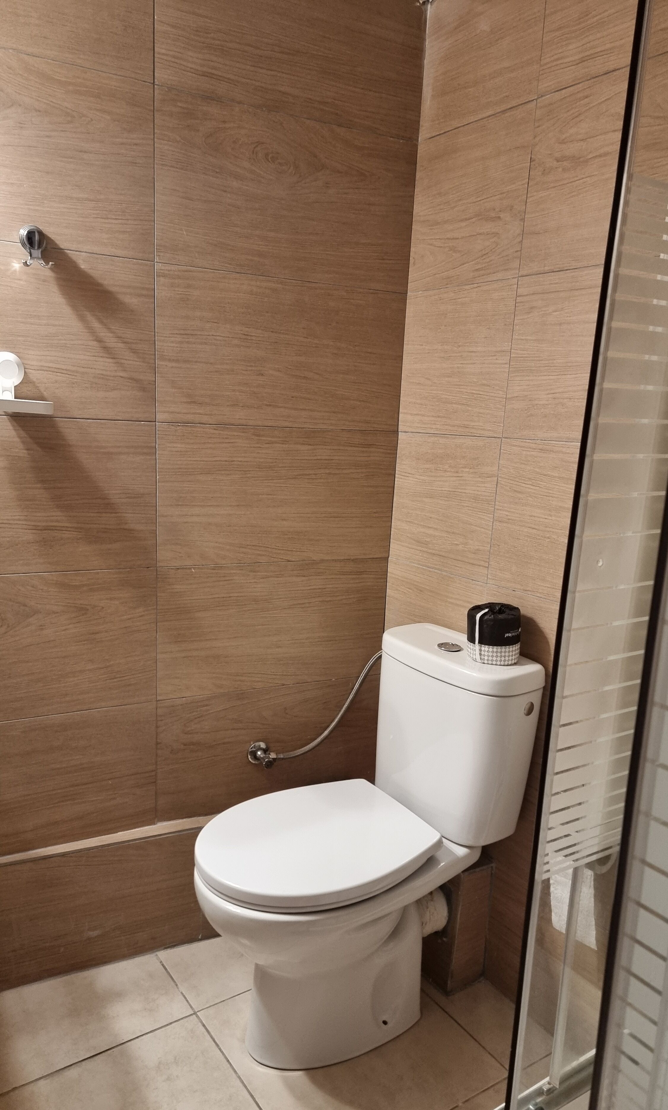 A modern bathroom with a white toilet, a shower area, and a glass door.