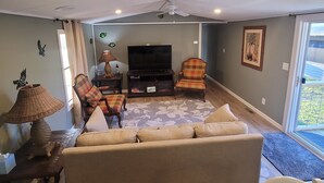 A living room with a sofa, two armchairs, a television, and a ceiling fan.