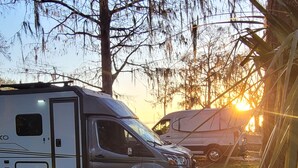A camping trailer parked in a grassy area with trees in the background.