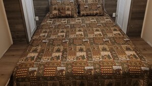A bedroom with a wooden headboard, a bed with patterned bedding, and a window with shutters.