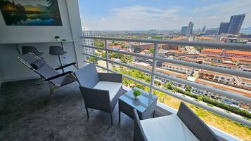 A balcony with wicker furniture, a small table with a plant, and a painting on the wall.