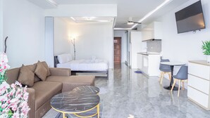 A modern hotel room with a sofa, a bed, a dining area, and a TV. - View Talay 5 - Beachfront Ocean View - High Floor & Huge Pool (Pattaya)