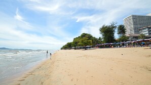 A beach with a row of beachside restaurants and a tall hotel building in the background. - View Talay 5 - Beachfront Ocean View - High Floor & Huge Pool (Pattaya)