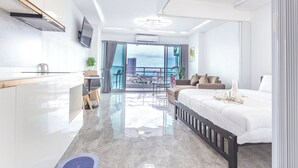 A modern hotel room with a balcony, a kitchen area, and a large bed. - View Talay 5 - Beachfront Ocean View - High Floor & Huge Pool (Pattaya)