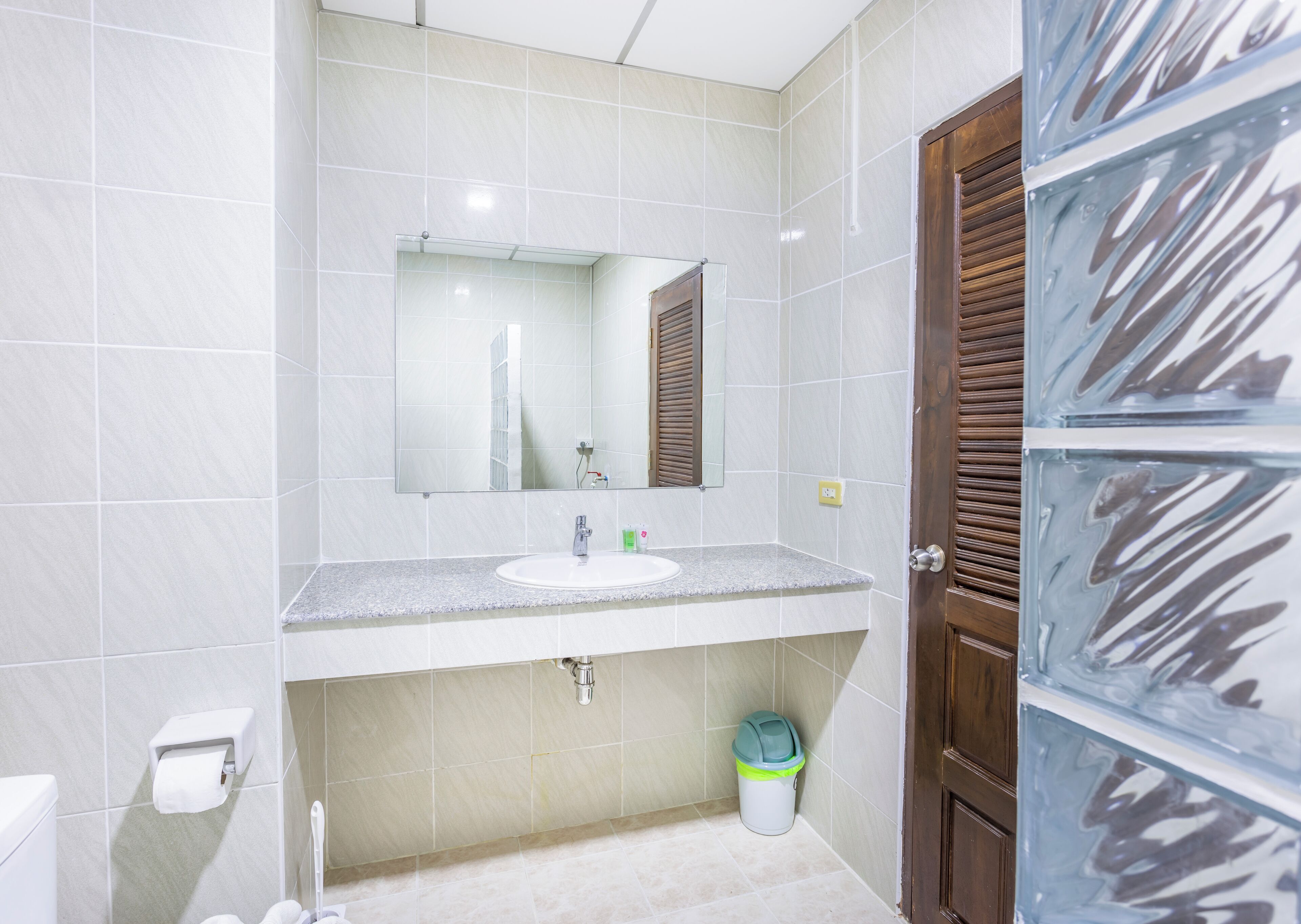 Un baño con lavamanos, espejo y retrete blancos.