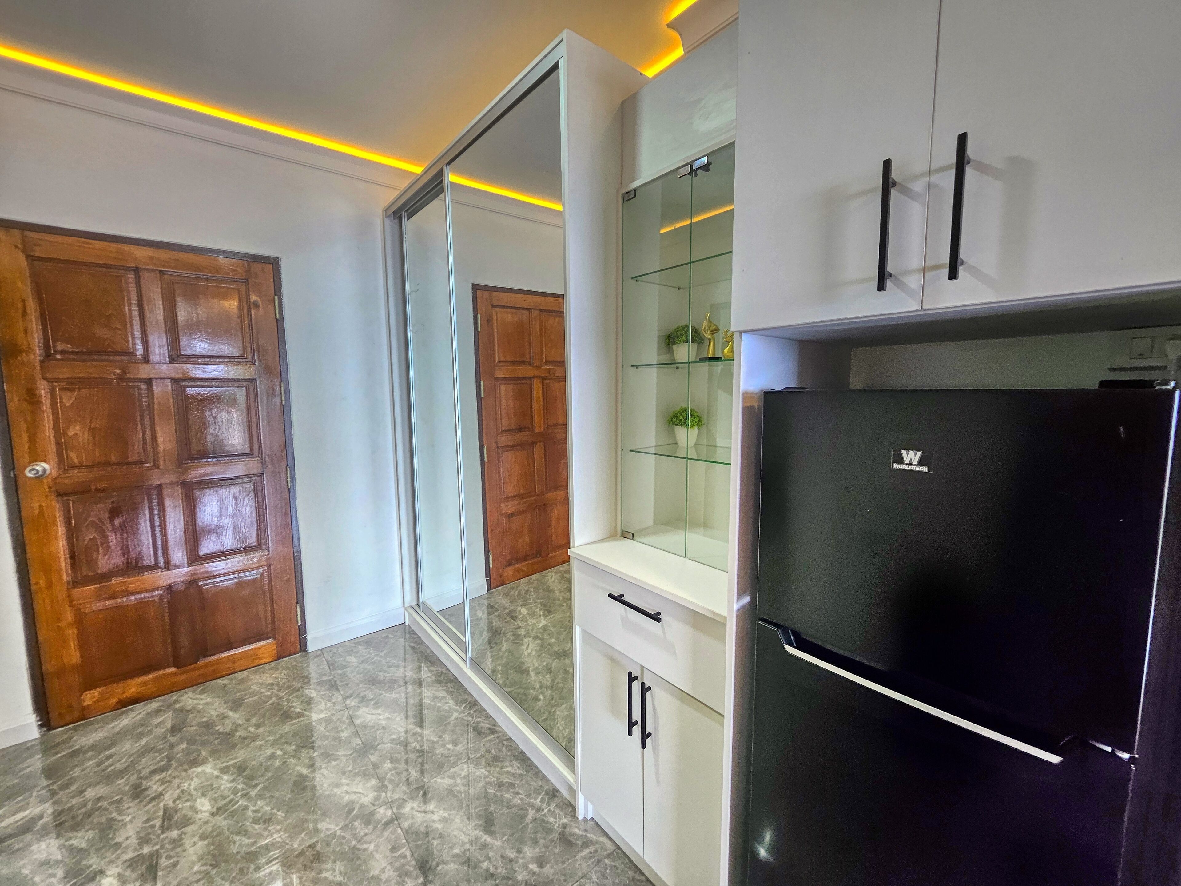 A modern kitchen with a black refrigerator, white cabinets, and a glass display cabinet.