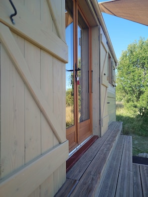 A wooden exterior with a sliding glass door, a wooden deck, and a clear sky.