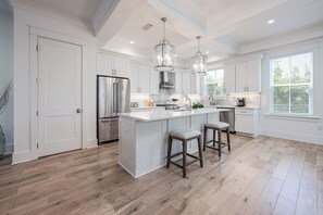 A modern kitchen with white cabinetry, a large island with bar stools, stainless steel appliances, and pendant lighting. - Simon Seas * Pet Friendly, Golf Cart Included, Grill, Lots of Space! (Miramar Beach)