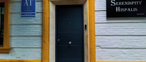 A building facade with a dark blue door, yellow trim, and a sign for 'Serendipity Hispalis'.