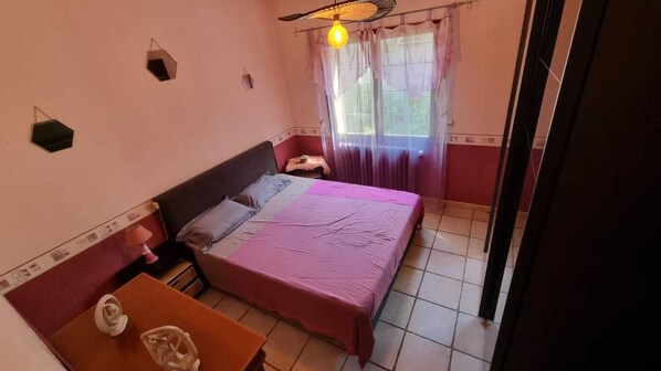 Une chambre à coucher avec un lit, une table et une fenêtre avec des rideaux.