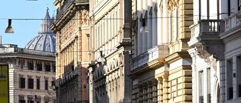 A street with historic buildings, a clear sky, and a few people walking.