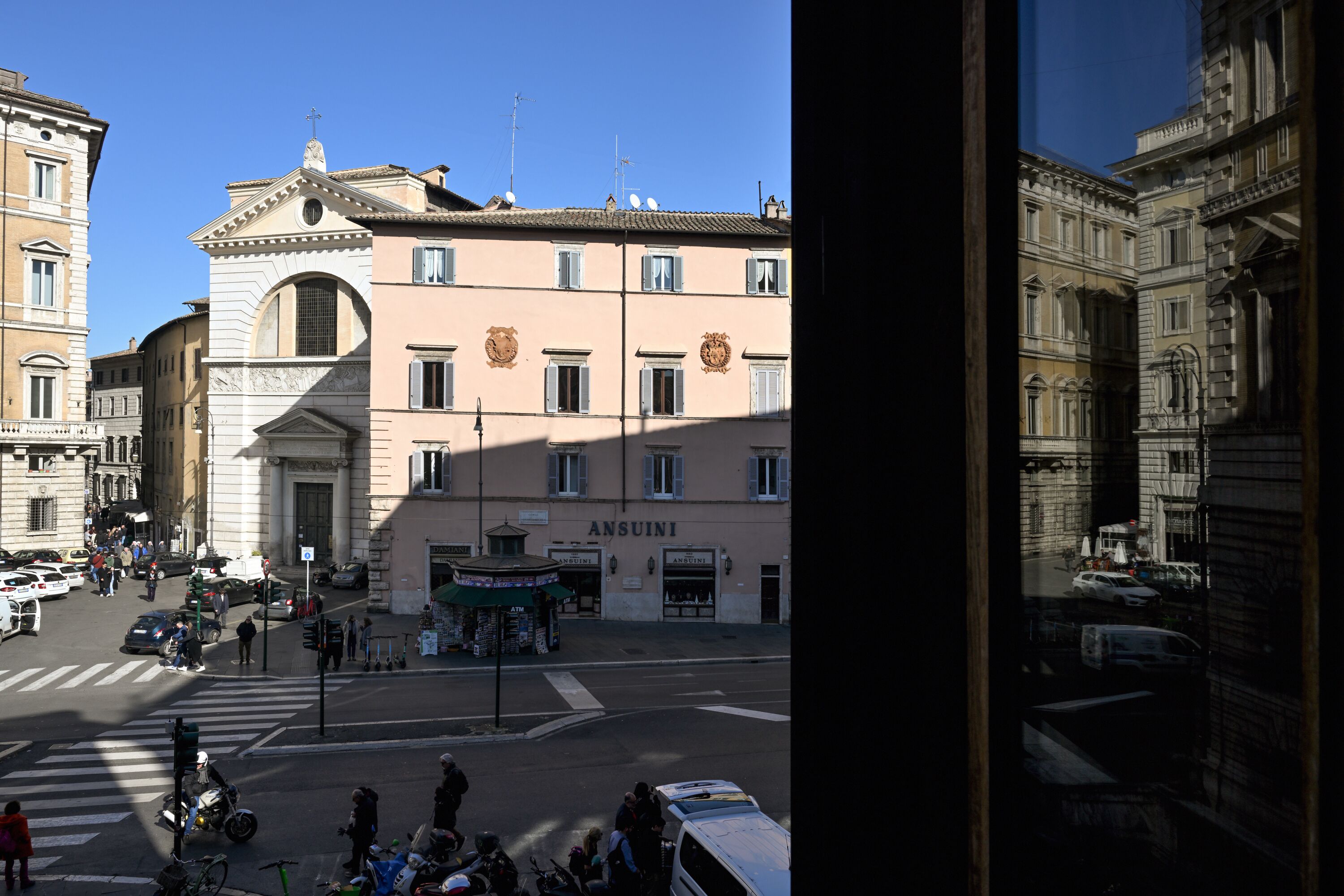 A building with a prominent entrance, a sign reading "ANSUINI," and a street view with vehicles and pedestrians.