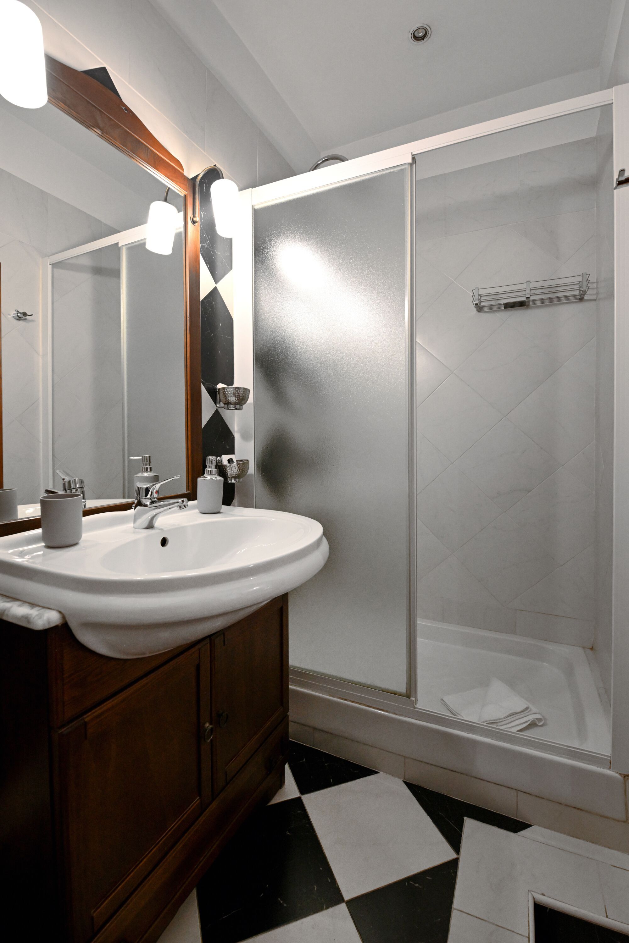 A bathroom with a white sink, a mirror, and a glass shower enclosure.