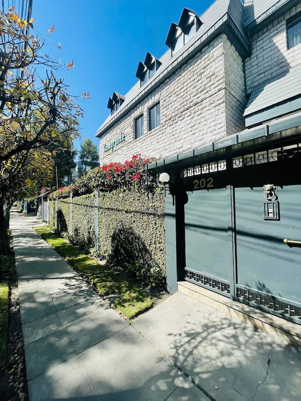 Un edificio con fachada de piedra, un letrero con el número 202 y una fila de ventanas.