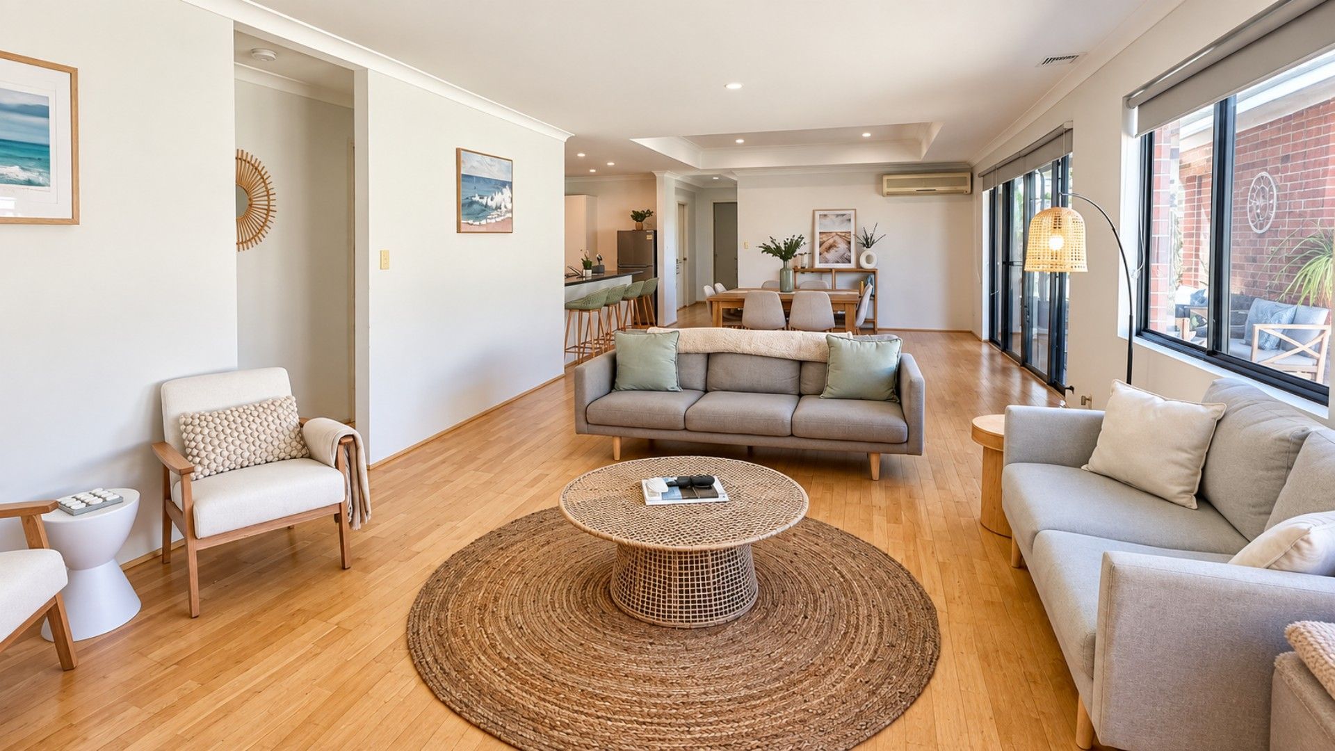 Un salon moderne avec un canapé, des fauteuils, une table basse et, au fond, un coin repas.