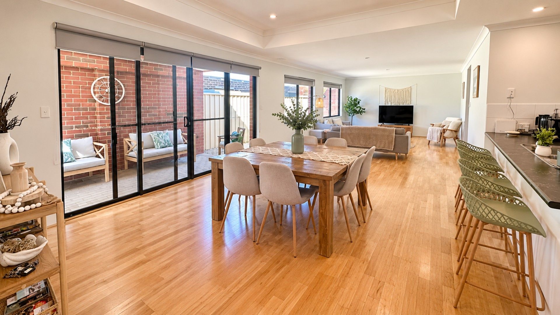 A spacious living area with a dining table, chairs, a sofa, and a TV.