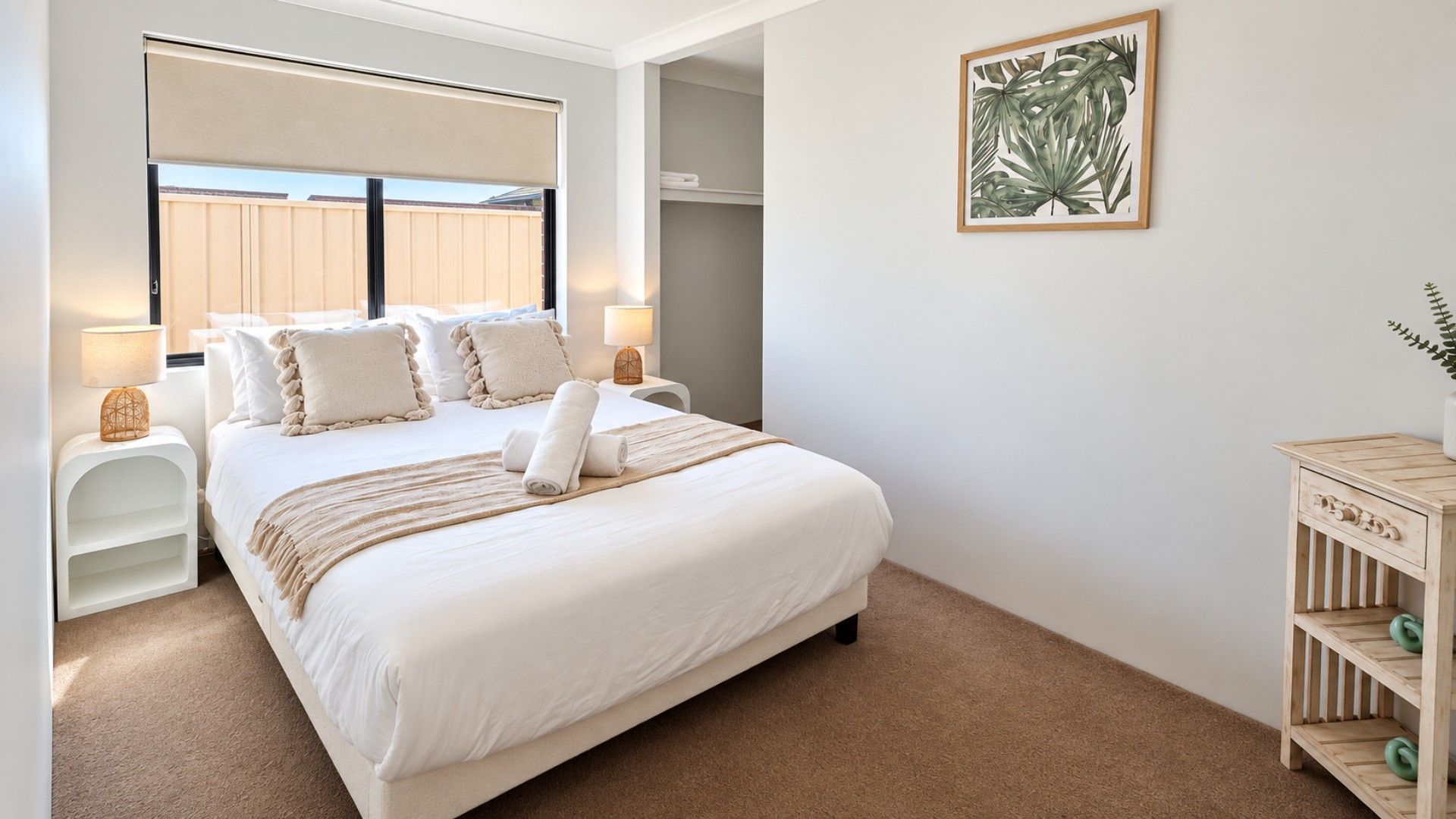 A bedroom with a large bed, bedside tables, a nightstand, a wall-mounted artwork, and a wooden cabinet.