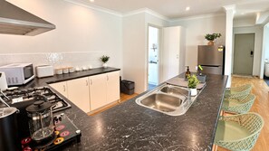A modern kitchen with a gas stove, microwave, toaster, and a large sink. - Eucalyptus Escape - Dunsborough (Dunsborough)