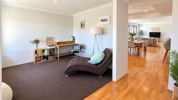 A modern living room with a brown sofa, a wooden desk, and a dining area with a TV.