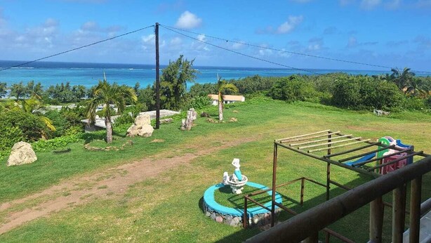 A view of a grassy area with a playground, a small pool, and a clear view of the ocean. - BELLE ÉTOILE OCEAN (Rodrigues Island)