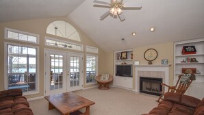 A spacious living room with a fireplace, comfortable seating, and large windows. - Crystal Clearwaters by Lake Martin Vibe (Dadeville)