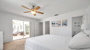 Une chambre avec un grand lit, un ventilateur de plafond et une vue sur un balcon.