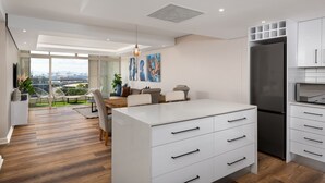 Una cocina moderna con armarios blancos, un refrigerador negro y un comedor con vistas.