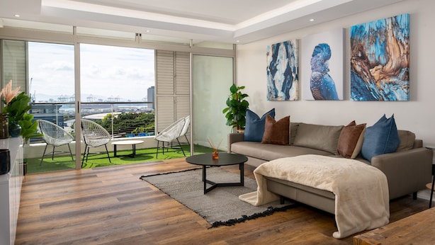 Una sala de estar moderna con sofá, mesa de centro y una obra de arte en la pared.