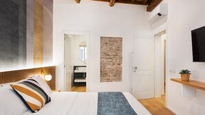 Een slaapkamer met een bed, een accentmuur van steen, een houten plafond en een wandmontage tv.