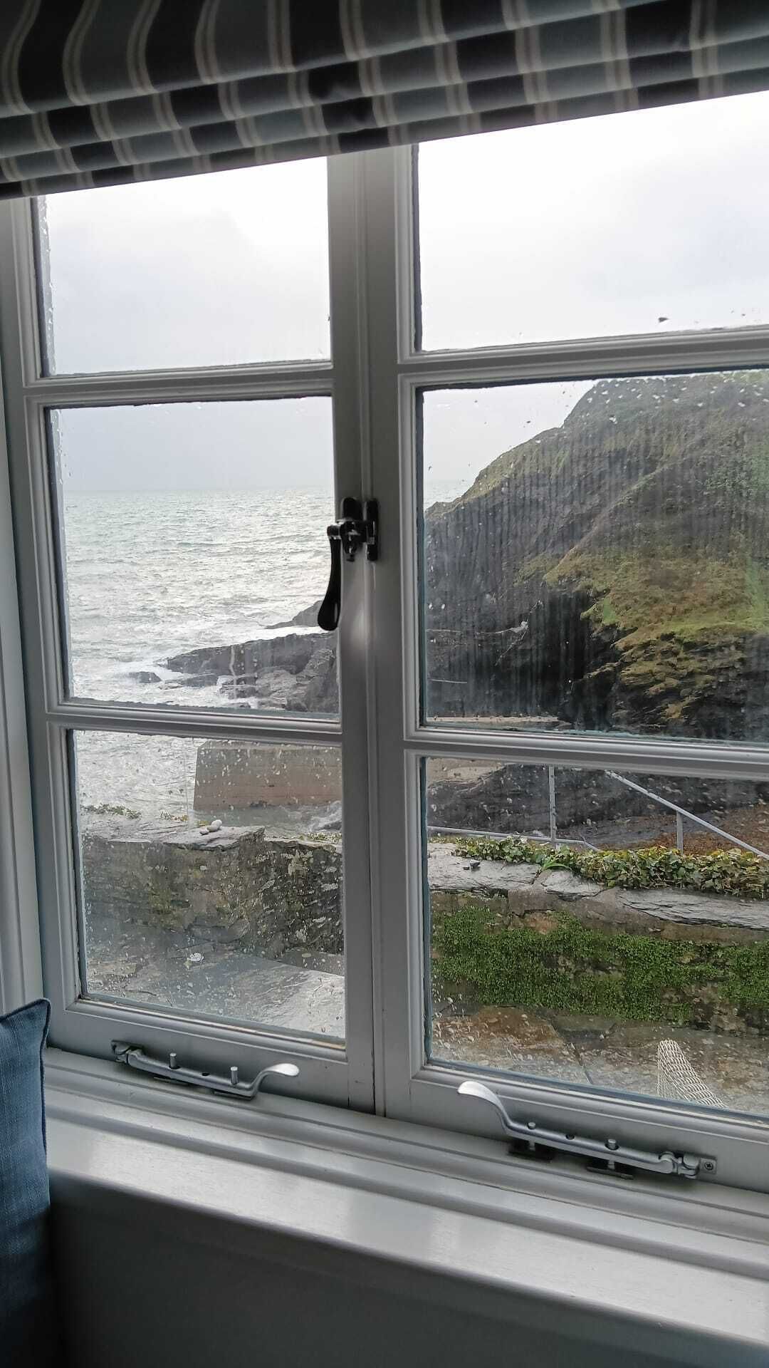 A window with a view of a rocky coastline and a mountain.