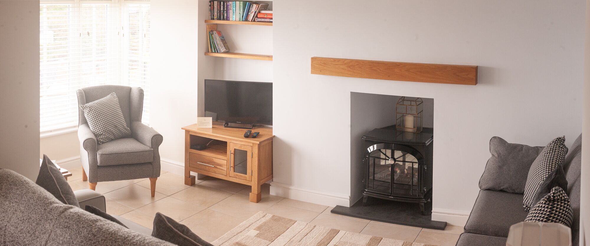 A living room with a grey sofa, a wooden TV stand, a fireplace, and a bookshelf.