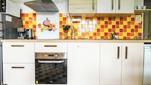 Een keuken met witte kastjes, een roestvrijstalen koelkast, een koffiezetapparaat en een magnetron.