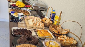 Una mesa de buffet con diversos alimentos, como pasteles, bollería y pan.