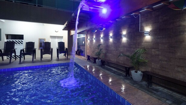 Una piscina interior con fuente, zona de estar y plantas en macetas.