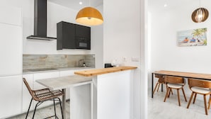 Una cocina moderna con una isla de madera, taburetes de bar y una lámpara colgante.