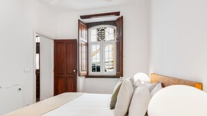 Un dormitorio con cama, almohadas, una ventana con vistas y una puerta de madera.