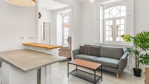 Una sala de estar moderna con un sofá gris, una mesa de centro de madera y una planta en maceta.